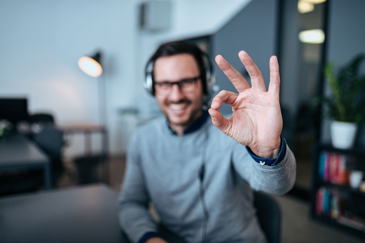 Happy male customer service operator showing okay sign in his office.